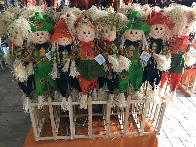 Colorful scarecrow dolls displayed for sale at market.