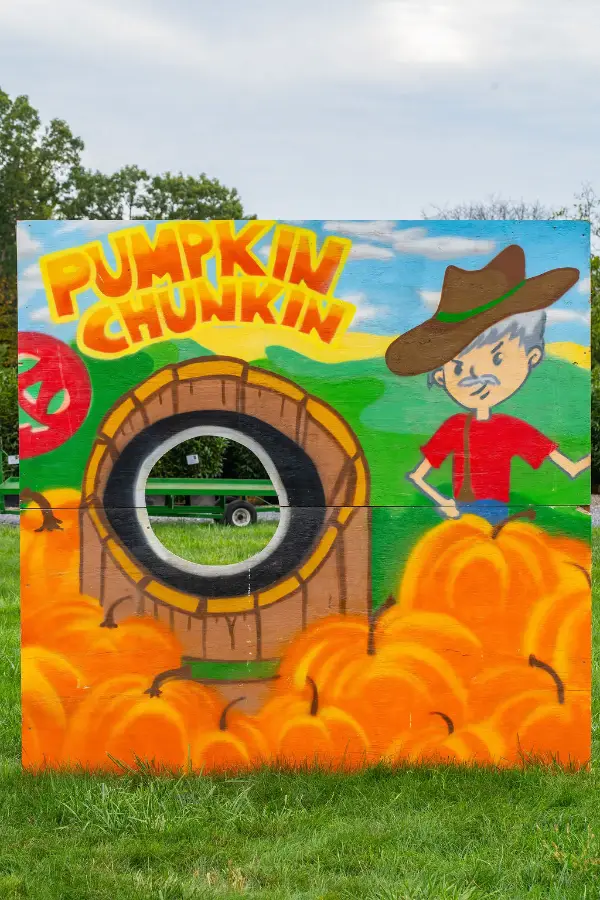 Colorful mural with "Pumpkin Chunkin" text, featuring a cartoon figure in a cowboy hat beside a large barrel in a field of pumpkins; cheerful and lively.