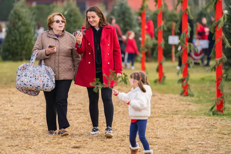 Family choosing Christmas tree at outdoor market.